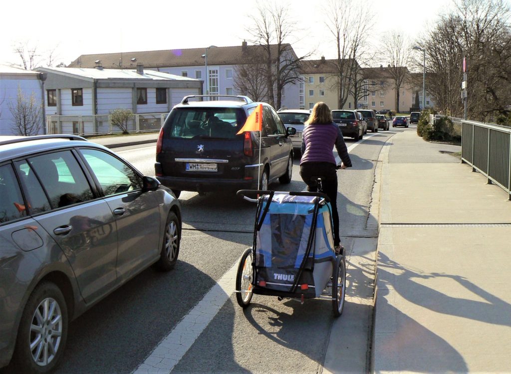 Radlerin fährt am Auto-Stau vorbei, Weilheim
